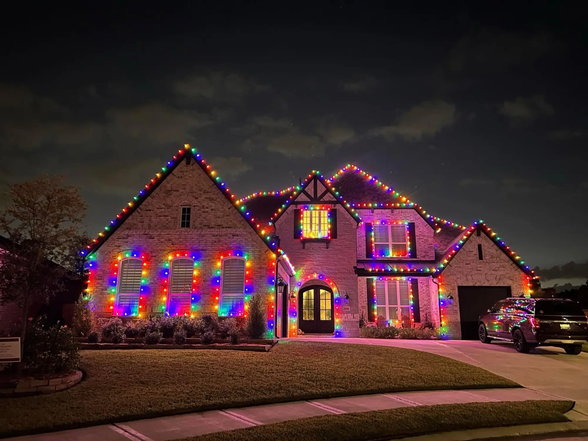 A large brick home outlined in multicolour bulbs with every window individually framed in lights